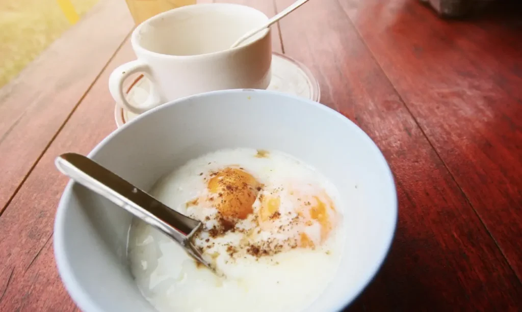 fried eggs, eggs in a white bowl next to cup od tea